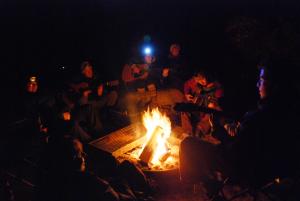 Humans gathered around an evening campfire.