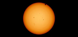 Image of the Sun during a transit of Venus. Sunspots can be seen as well as the shadow of Venus can be seen at the upper right. The edge of the Sun is slightly darker, which is an effect known as limb darkening.
