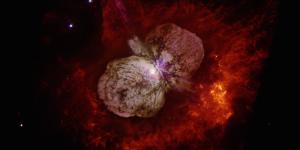 A color image from the Hubble Space Telescope of the Eta Carinae star system surrounded by a dumbbell-shaped cloud of gas and dust.