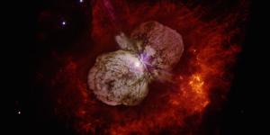 A color image from the Hubble Space Telescope of the Eta Carinae star system surrounded by a dumbbell-shaped cloud of gas and dust.