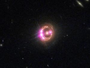 The four bright magenta points are images of a single quasar, magnified and multiplied by the gravity of the galaxy.