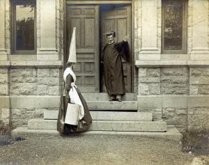 A female student in a dunce cap and a man on the steps of the Tome Scientific Building of Dickenson College around 1890.
